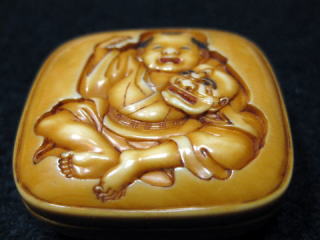 AKAEBISUDO TANAGOKORO,HOJITSU SIGNED MANJYU NETSUKE CHINESE BOY PLAYS MASK OF OLD MEN JPG03